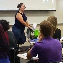 Teacher speaking to students, who are seen from rear