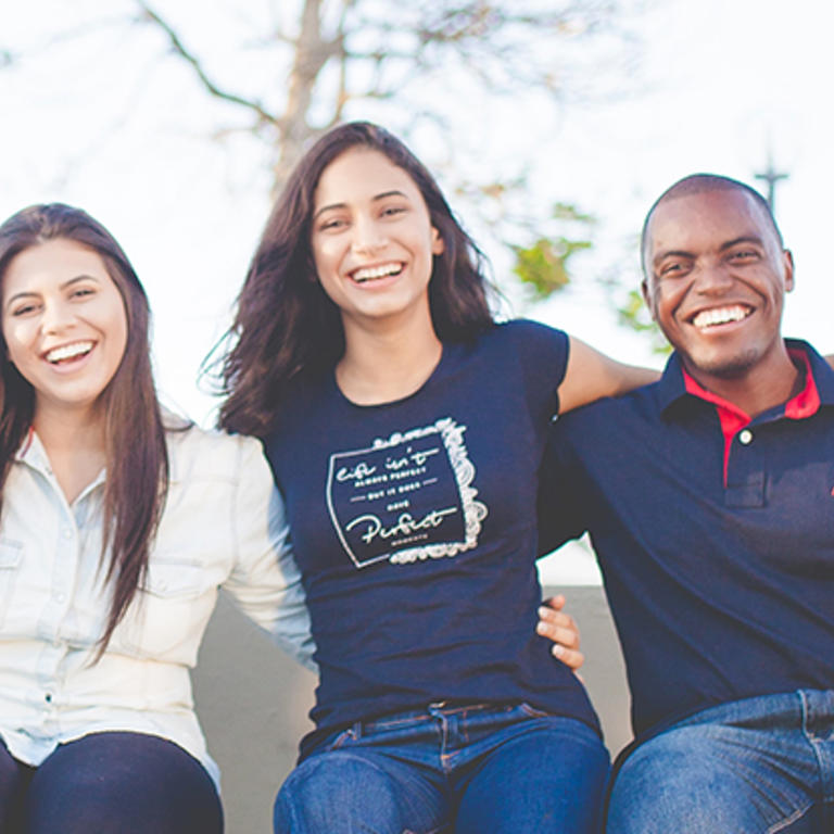 students sitting in a row outdoors smiling at camera