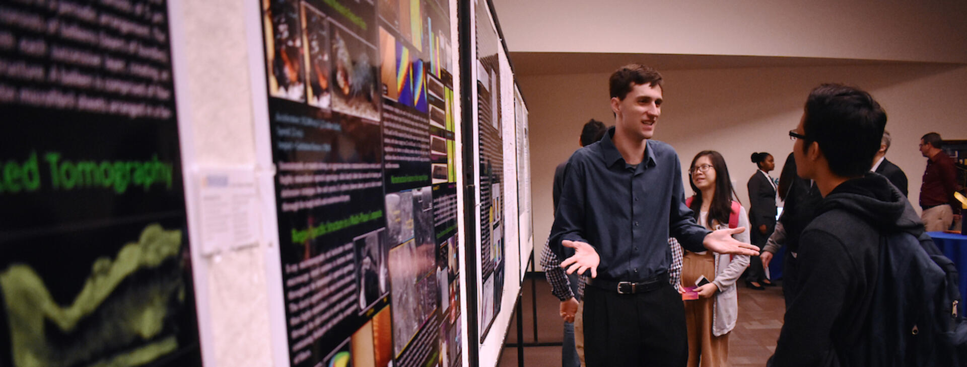 student explaining research poster to another student